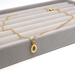 Detail of a gold stainless steel necklace with a minimalist capital O letter pendant
