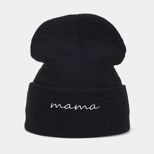 Dettaglio del berretto in maglia nera con ricamo mama bianco sul bordo ripiegato