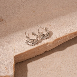 Macro detail of silver C-shaped geometric earrings with sparkling pavé zircon stones