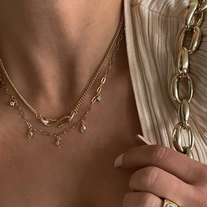 Detail of layered gold snake necklace featuring zircon pendants on a female model