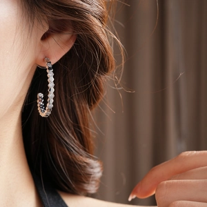 Détail de la boucle d'oreille hexagonale en C argentée avec zircons sur le mannequin