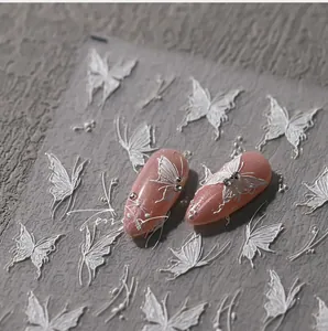Detail of white 3D butterfly nail stickers on pink glitter nails with stone backdrop
