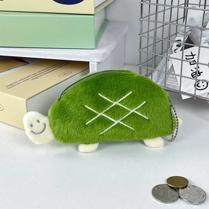 Detail shot of a plush green turtle coin purse with silver zipper and beaded chain