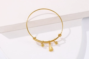 Close-up of golden guitar pendant on a wire bracelet over white geometric steps