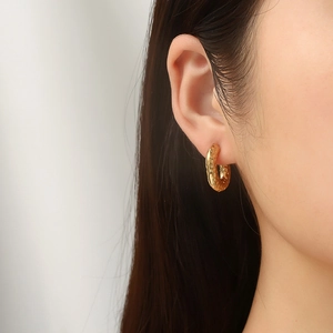 Elegant 18K gold-plated oval earrings with hammered texture shown on a female model