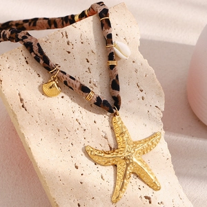Detail of 18K gold plated starfish pendant with leopard print strap on a natural stone