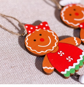 Close-up of wooden gingerbread girl ornament with red bow on beige fabric texture
