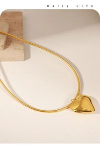Detail view of a minimalist gold heart pendant on a sleek snake chain necklace