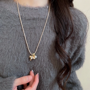 Gros plan du pendentif cheval doré avec perle sur un pull en maille douce et élégant