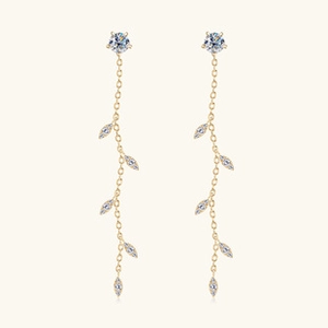 Detail of elegant gold tassel earrings with leaf-shaped stones and moissanite accents