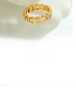 Detailed shot of a gold-plated ring with baguette-cut zircons on a white ceramic plate