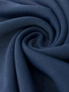 Gros plan du tissu en maille bleu foncé montrant la texture douce et le drapé