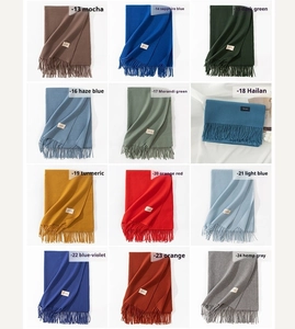 Detail view of 12 solid color cashmere-style scarves with fringes and woven textures