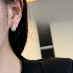 Macro side view of elegant water drop stud earrings with sparkling stones on a model