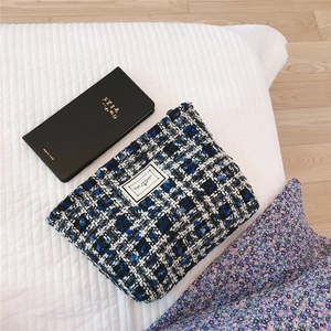Detail of blue and black tweed cosmetic bag featuring TIME TO PARTY label on quilted fabric
