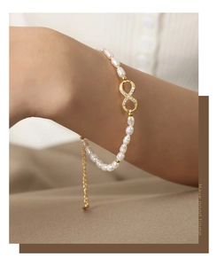 Detail of elegant pearl bracelet with golden infinity charm and sparkling crystals
