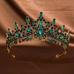 Detail of golden bridal crown with intricate green and black gemstone inlay on silk