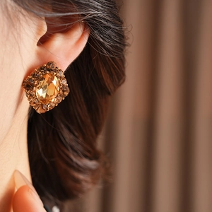 Gros plan de boucles d'oreilles vintage en cristal ambre avec strass sur l'oreille du mannequin
