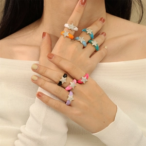 Detailed view of colorful enamel star rings with zircon stones worn on hands