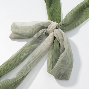 Detail of knotted green and beige headband with pleated texture and subtle shimmer