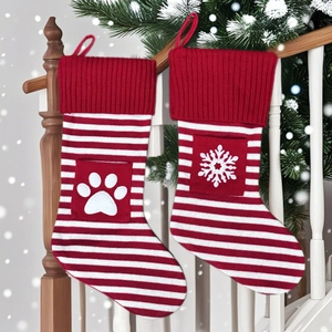 Chaussettes de Noël tricotées avec motifs de pattes et flocons sur un escalier