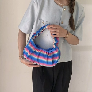 Detailed view of the gradient pleated shoulder bag worn by a model against a white wall
