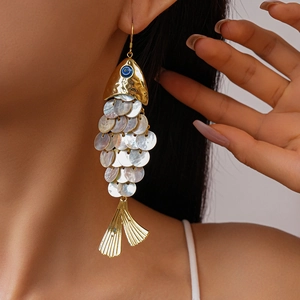 Detailed shot of fish-shaped tassel earring with white shell scales and blue evil eye bead