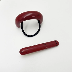 Detail view of red marbled resin U-shaped hair ring and matching hair pin set