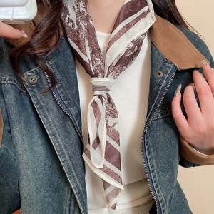 Detail of silk-feel scarf with vintage brown artistic print styled as a neckerchief