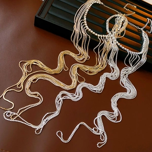 Détail de colliers à pompons argentés et dorés avec strass étincelants sur cuir brun