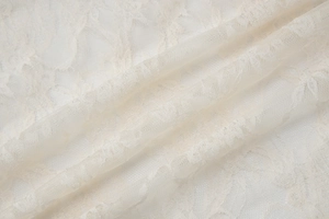 Macro detail of creamy white lace fabric showing intricate mesh texture and soft patterns
