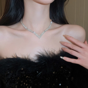 Close-up of V-shaped sparkling diamond necklace worn with black sequin evening dress