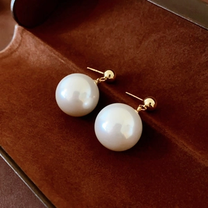 Detailed view of elegant pearl drop earrings with gold studs in a velvet jewelry box
