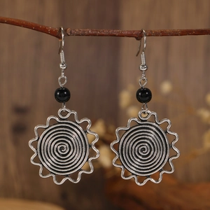 Pendientes de plata vintage en espiral con cuentas negras en una rama de madera natural