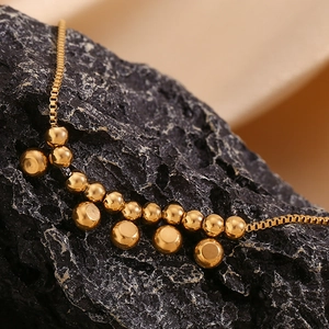 Detailed shot of a 18K gold-plated stainless steel anklet with beads on a dark rock