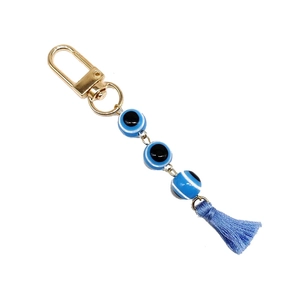 Close-up of golden keychain with blue resin evil eye beads and decorative tassel