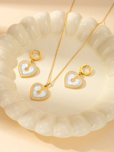 Elegant gold titanium heart jewelry set featuring necklace and earrings with white shell