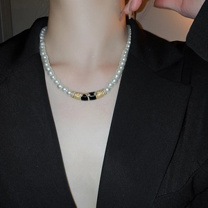 Détail d'un collier ras du cou en perles avec pendentif émail noir et diamants