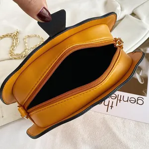 Close-up of yellow pumpkin bag opening with gold chain strap and black lining