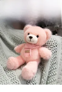 Close-up of pink teddy bear plush with knitted scarf and smile leather label detail