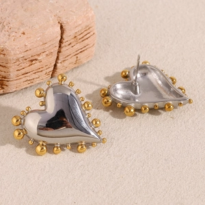 Close-up of heart-shaped two-tone stainless steel earrings with gold beaded edges