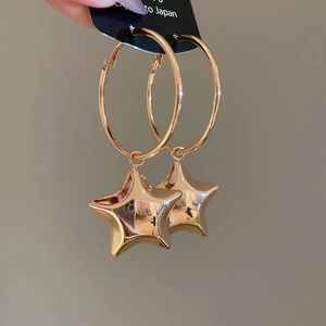 Dettaglio macro di orecchini a stella in oro lucido su un'elegante scheda di esposizione