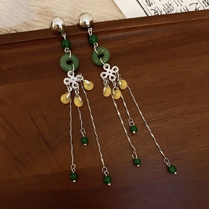 Detail of Chinese style tassel earrings with green beads on vintage wooden tray