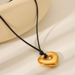 Macro shot of 3D golden heart pendant on black cord necklace for women's jewelry