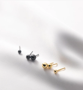 Detailaufnahme der minimalistischen runden Kugel-Ohrstecker in schickem Gold und Schwarz.