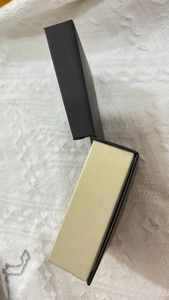 Detail showing flap cover jewelry box with black exterior and beige inner tray for necklaces