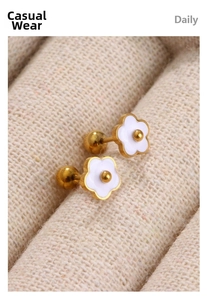 Detail of 18K gold daisy earrings with white enamel petals and secure screw back design