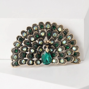 Detailed close-up of a vintage peacock brooch with green gemstones and sparkling rhinestones