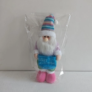 Detail of plush Christmas gnome doll with colorful striped hat and Merry Christmas sign