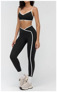 Detail of high-waist black yoga leggings and V-neck sports bra with white contrast piping